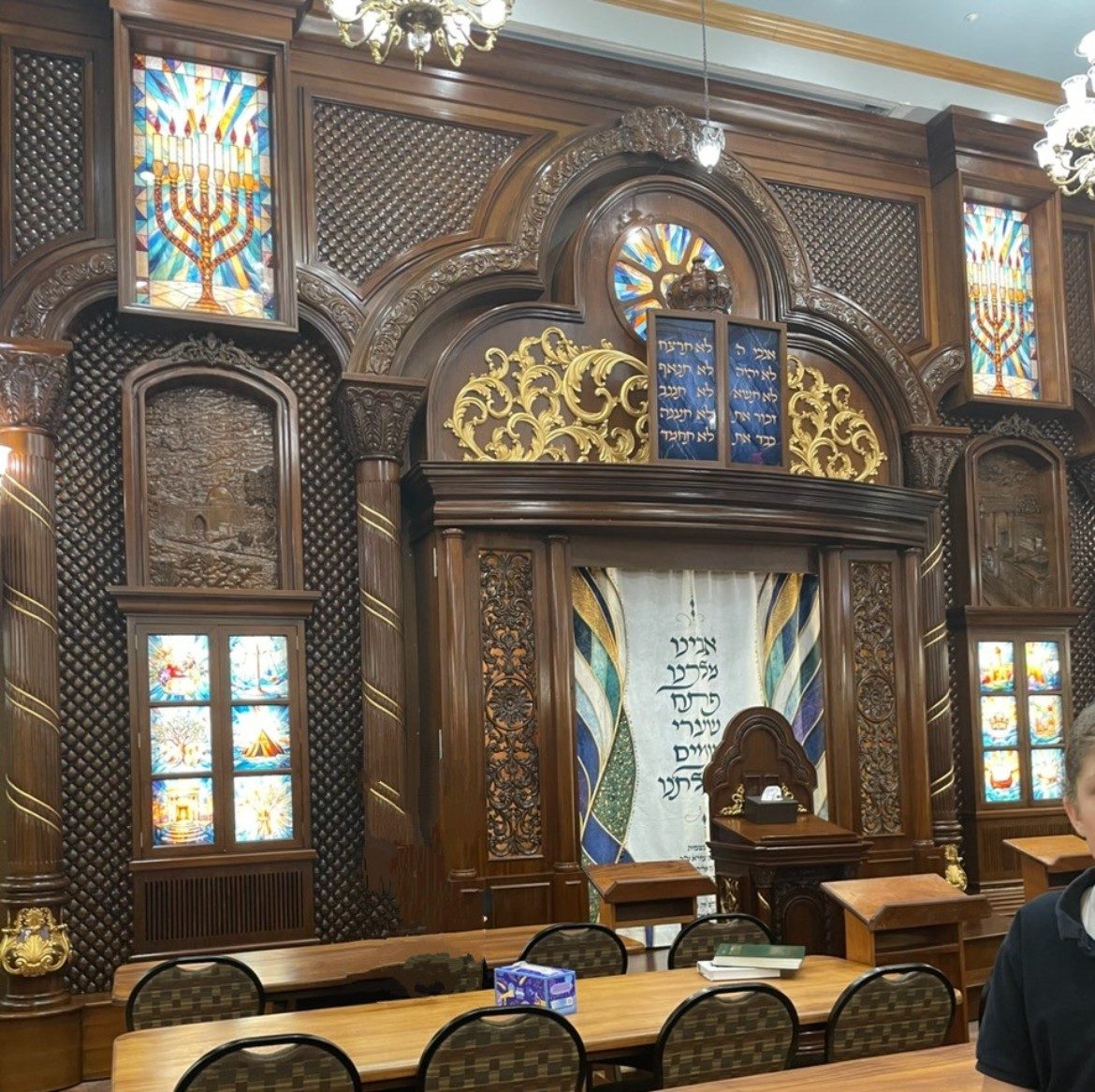 The aron kodesh at Kollel Ner Avrohom, wooden doors with gold carving and blue stained glass.